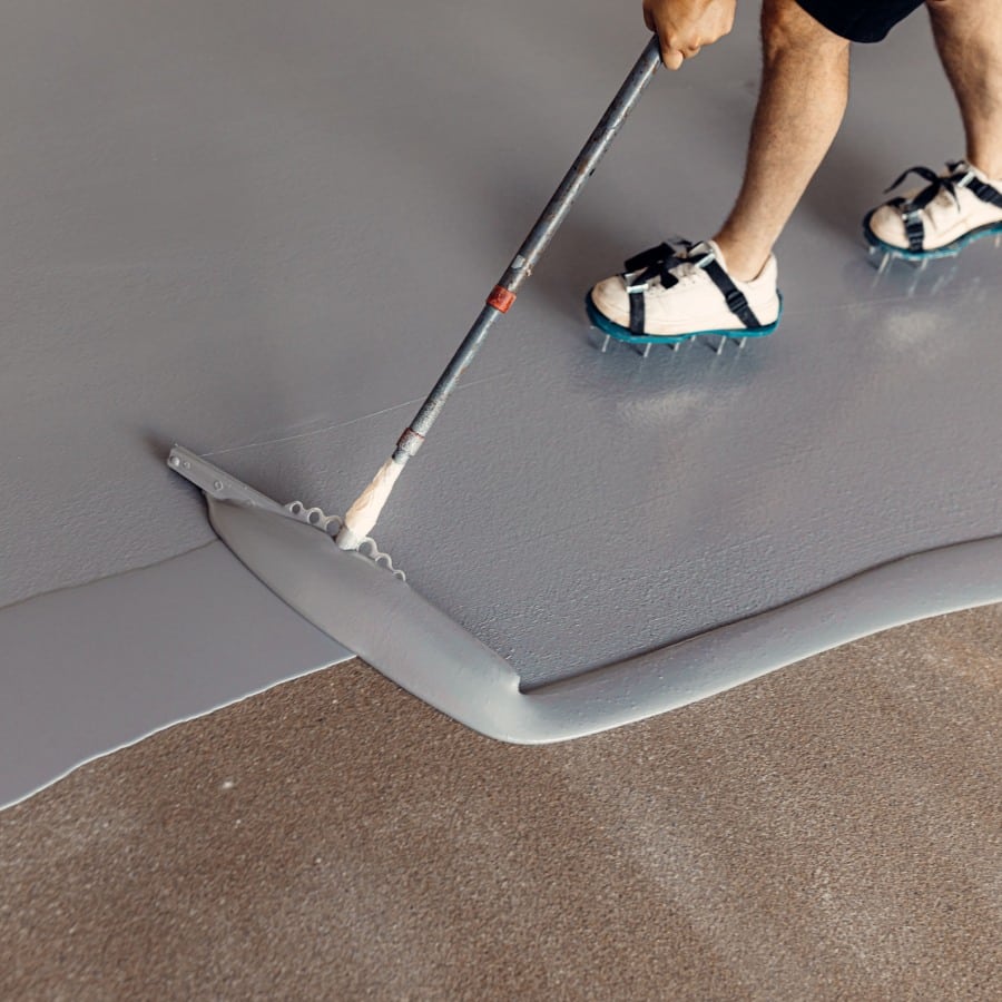 construction worker applying grey epoxy resin industrial hal