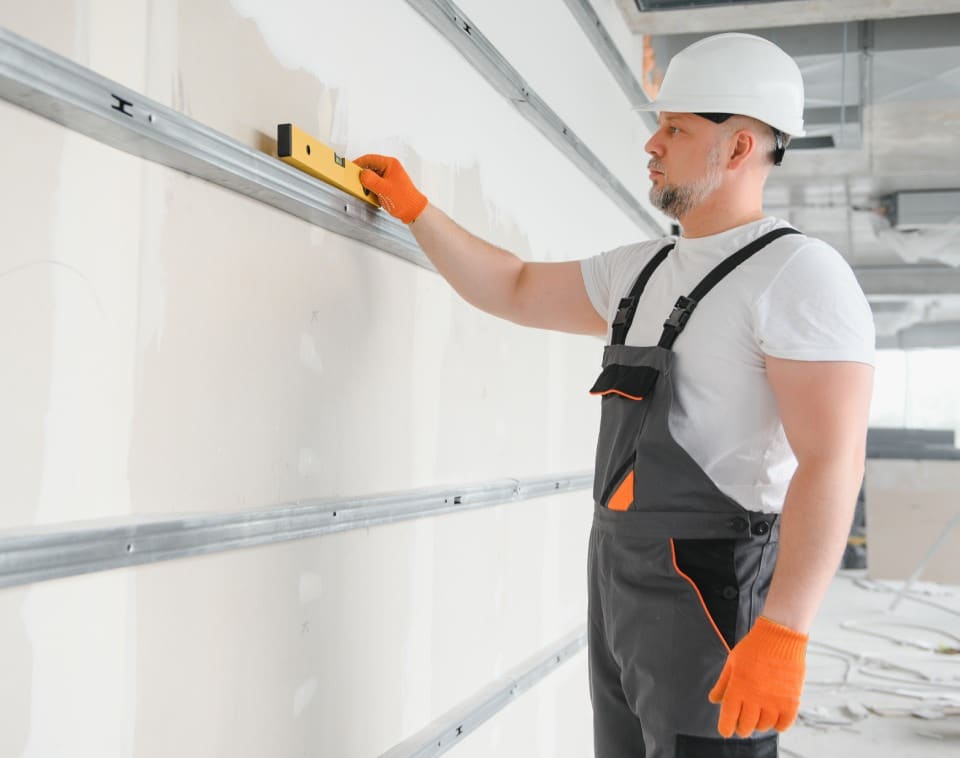 man holding level plasterboard interior drywall attic renovation